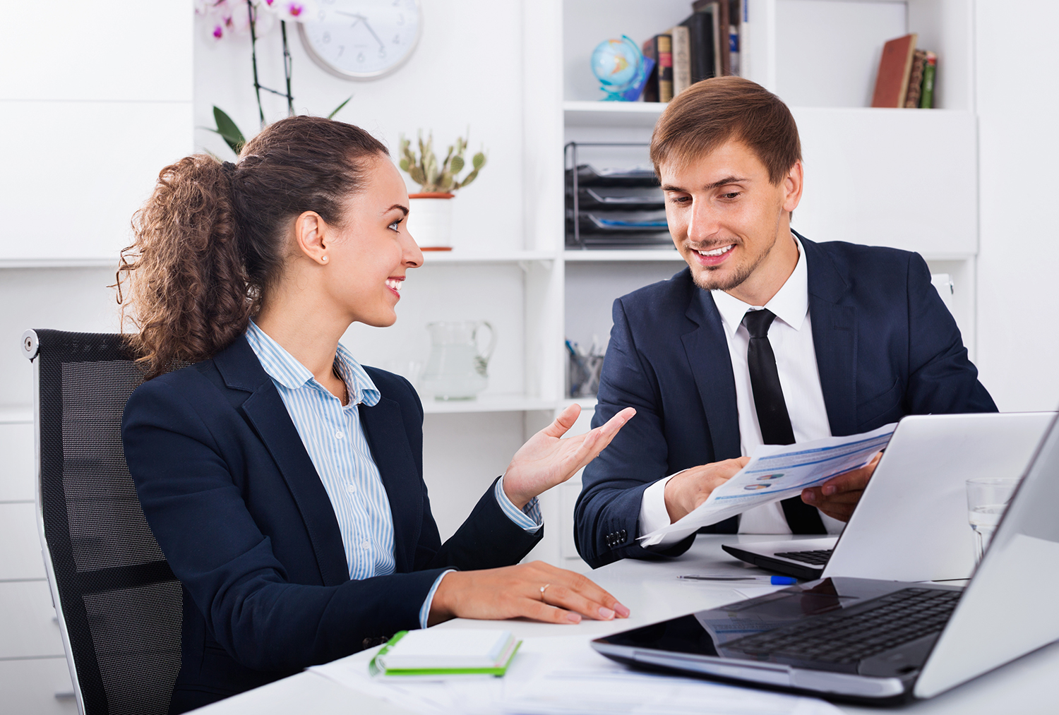 Two business male and female assistants wearing formalwear havin